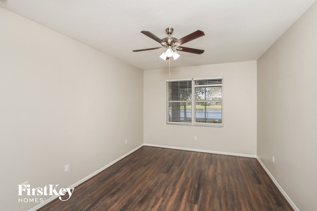 a spacious living room with hardwood floors and a ceiling fan