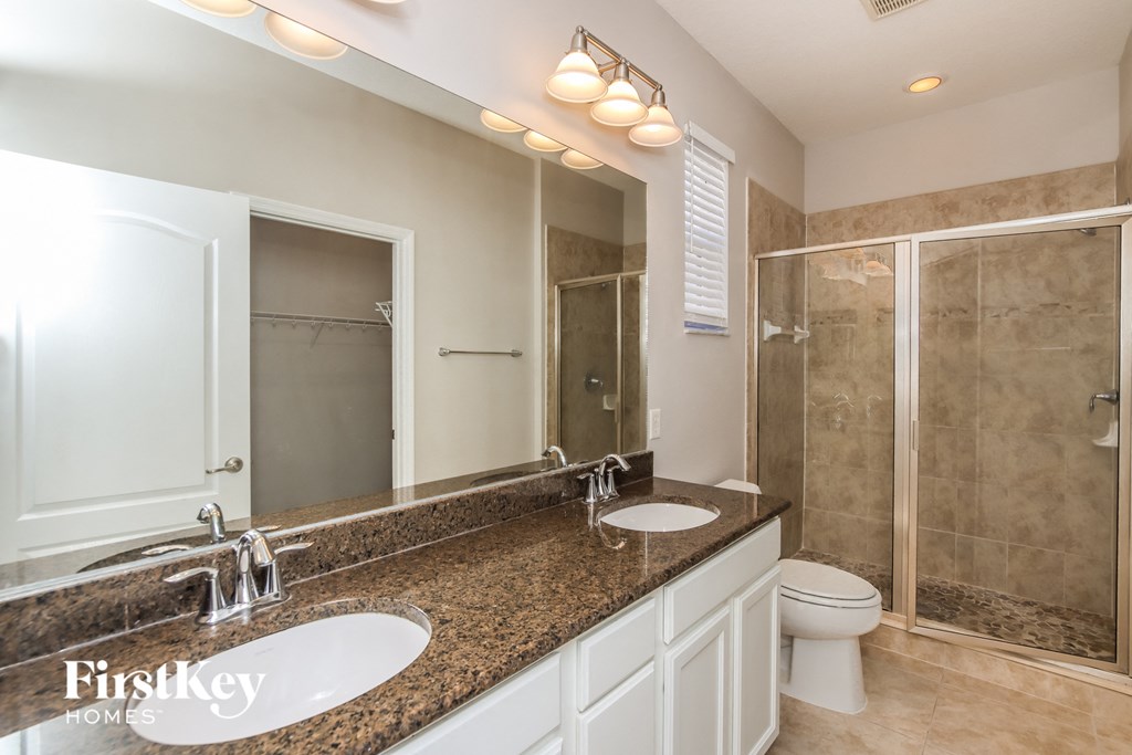 a bathroom with two sinks and a shower and a toilet