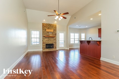 A spacious room with wooden floors and a stone fireplace.