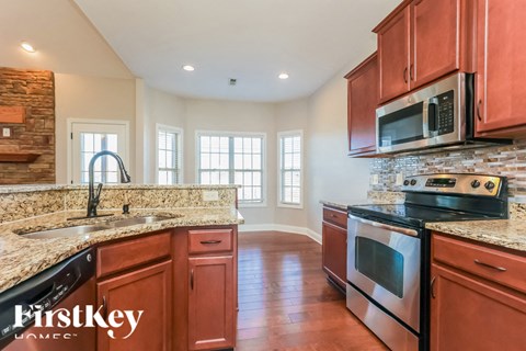 A kitchen with brown cabinets and a stone wall.