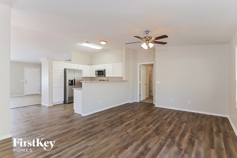 A spacious living room with wooden flooring and a ceiling fan.