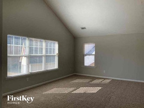 an empty room with two windows and a carpeted floor