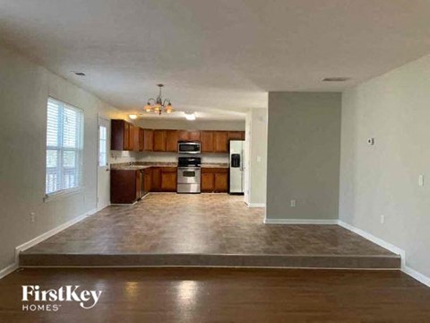 an empty living room and kitchen with wood floors