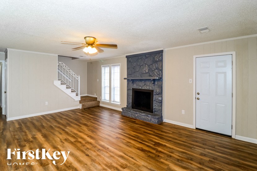 A spacious room with a fireplace and wooden floors.