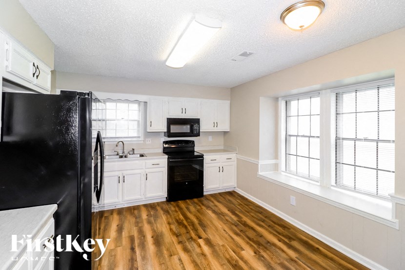 A kitchen with white cabinets and a black fridge.