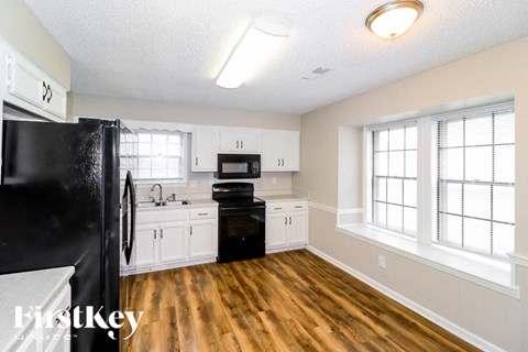 A kitchen with white cabinets and a black fridge.