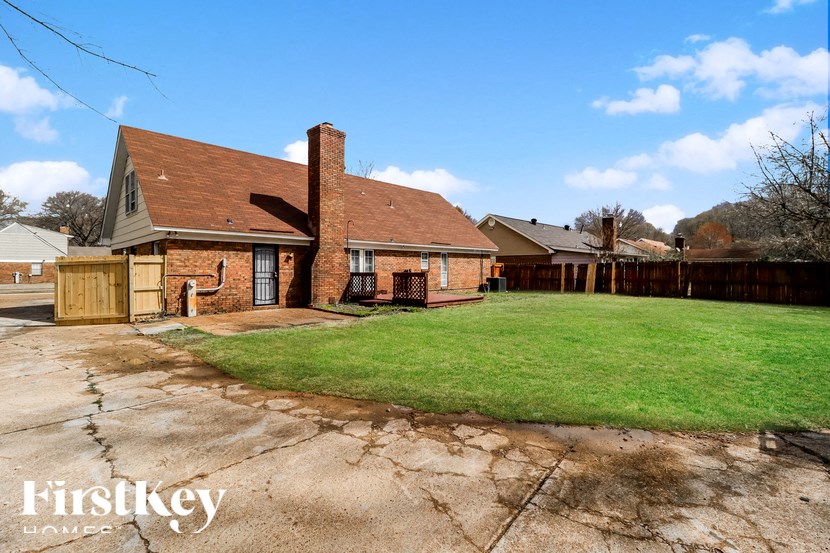 A brick house with a chimney and a grassy yard.