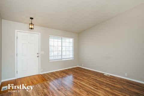 the living room of a home with a wooden floor and a white door