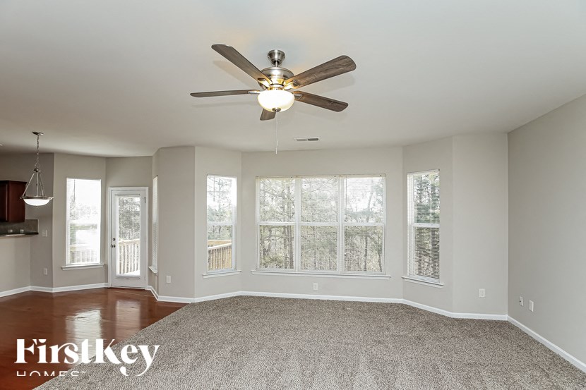 A spacious room with a ceiling fan and a carpeted floor.