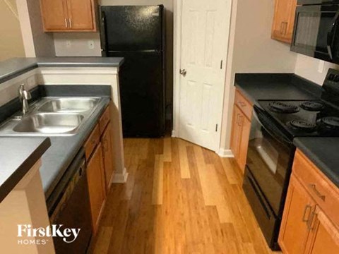 A kitchen with wooden floors and black appliances.