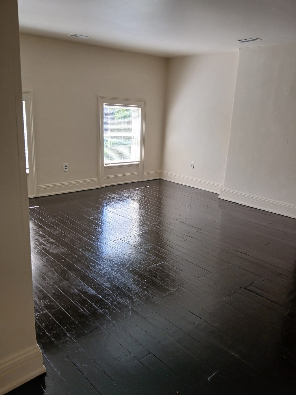 an empty living room with wooden floors and a window