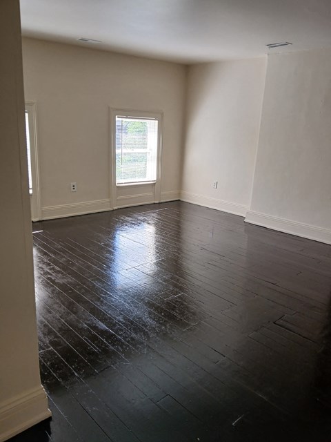 an empty living room with wooden floors and a window