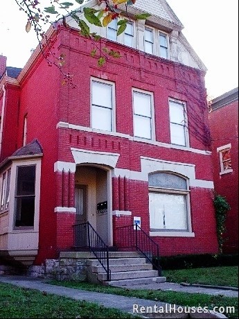 A red brick house with a black iron railing on the steps.