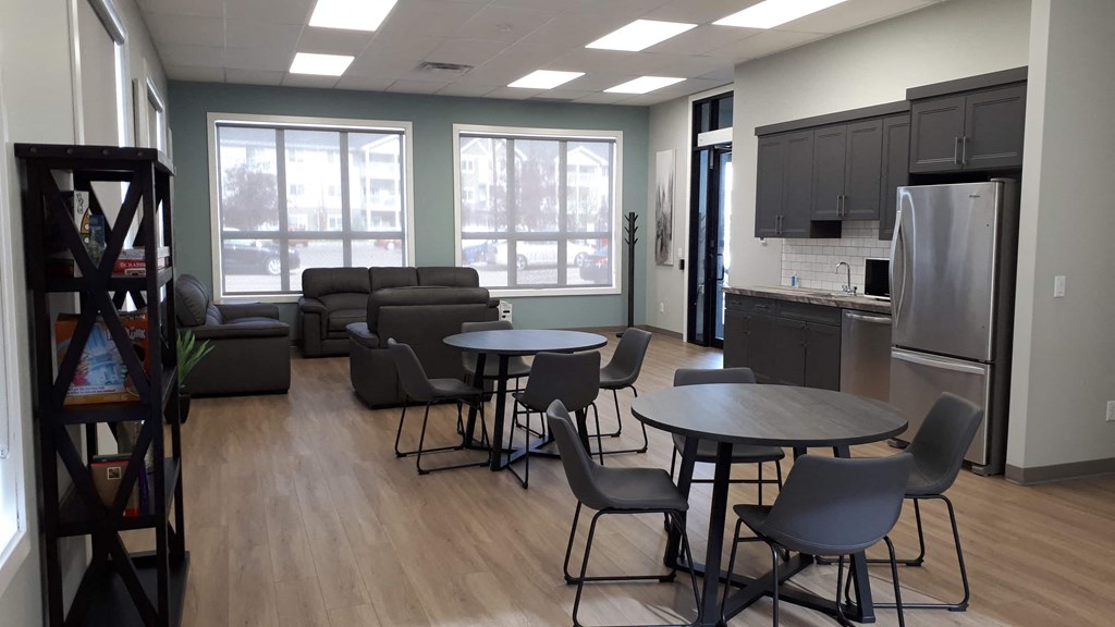 A kitchen area with a refrigerator, a dining table with chairs, and a sofa.