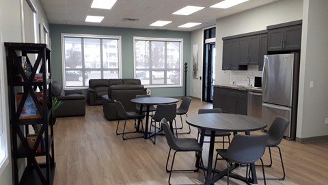 A kitchen area with a refrigerator, a dining table with chairs, and a sofa.
