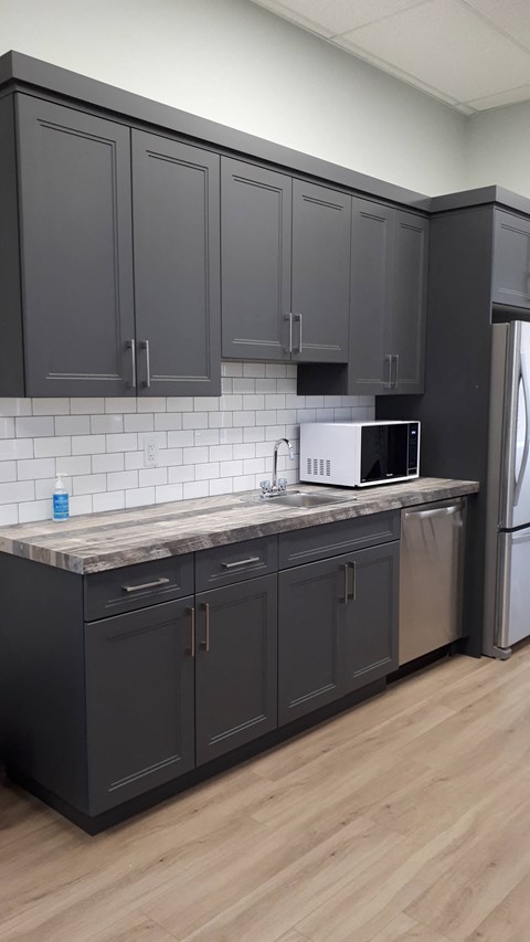 A kitchen with dark cabinets and a white fridge.