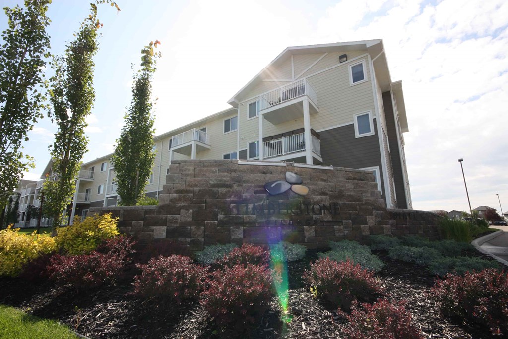A modern house with a stone wall and a balcony.