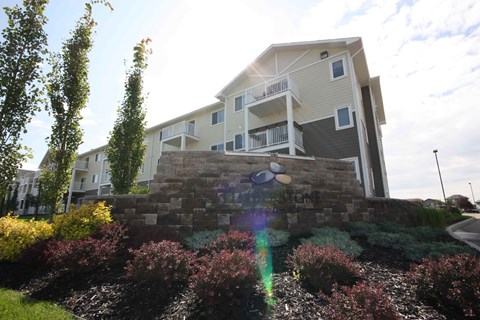 A modern house with a stone wall and a balcony.