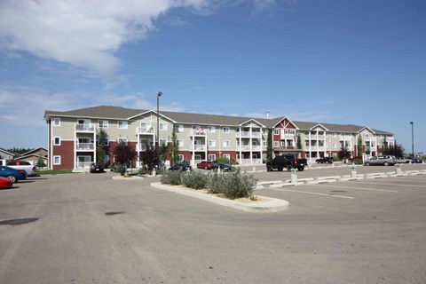 A parking lot in front of a large apartment complex.