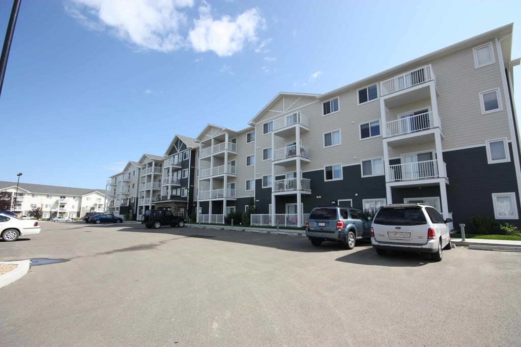 A parking lot in front of a row of apartment buildings.
