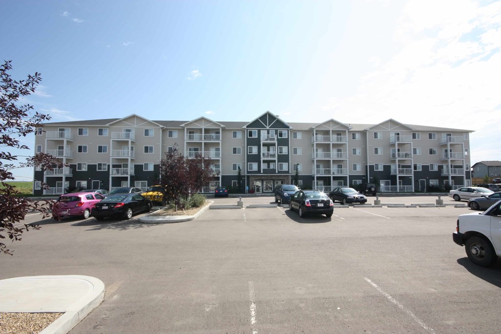 A parking lot in front of a large apartment building.