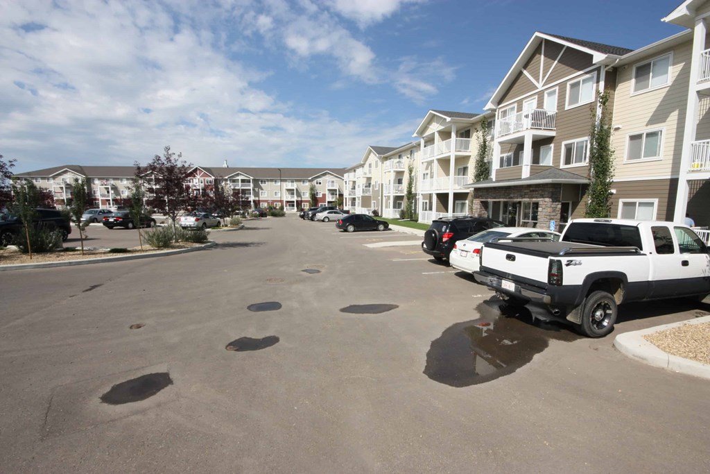 A parking lot with several cars and apartment buildings in the background.