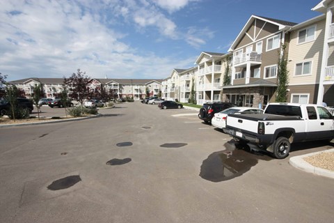 A parking lot with several cars and apartment buildings in the background.