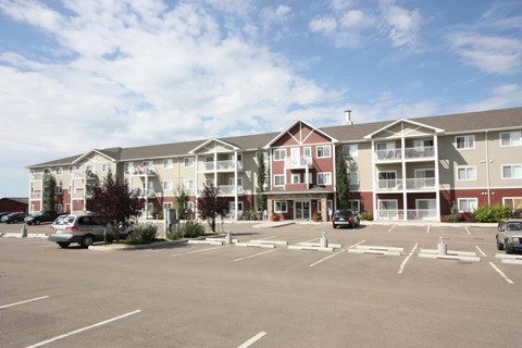 A large apartment complex with a parking lot in front.