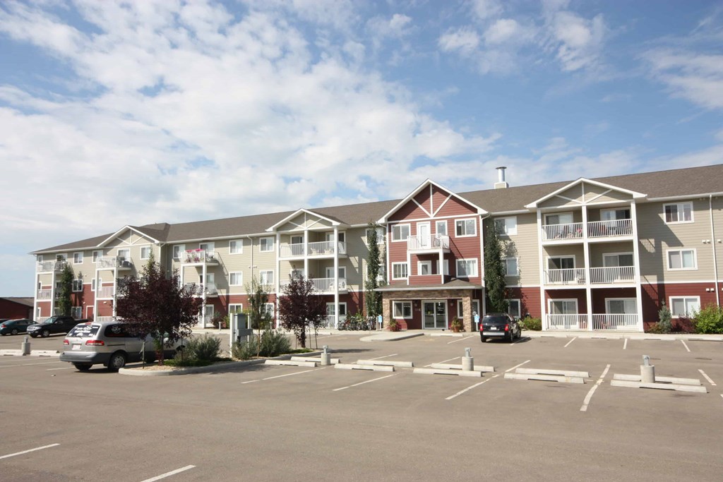 Apartment complex with a parking lot in front.