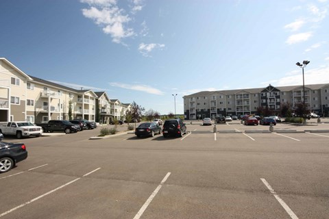 A parking lot with cars and apartment buildings in the background.