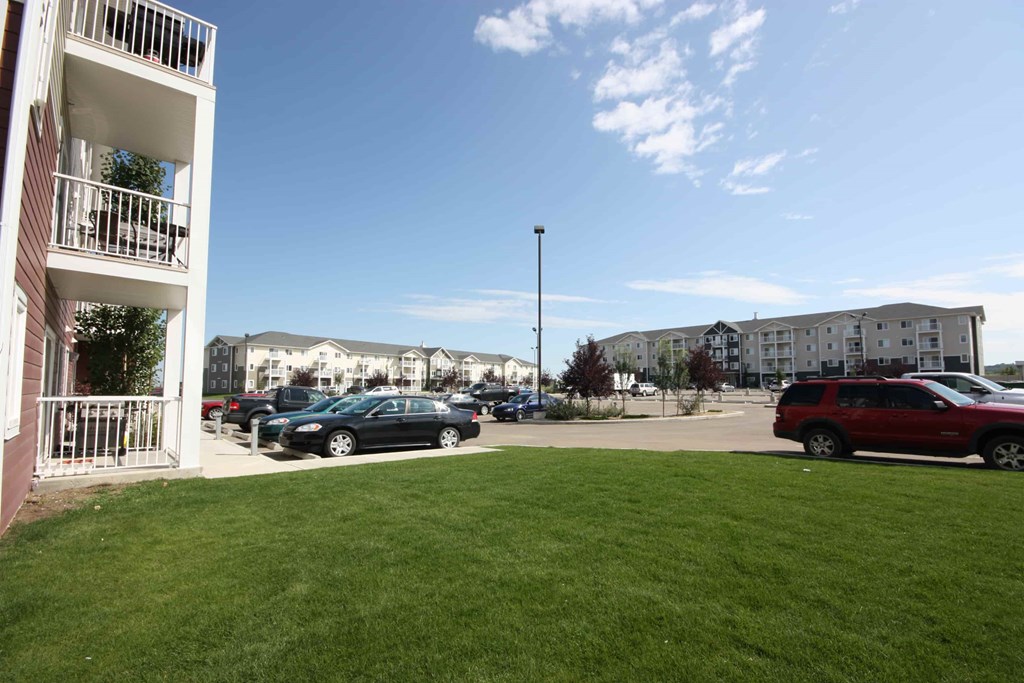 A parking lot with cars and apartment buildings in the background.