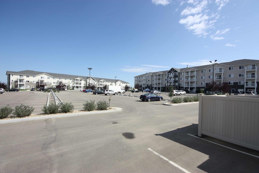A parking lot with cars and apartment buildings in the background.