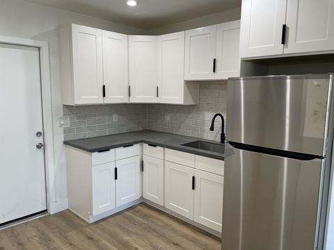a small kitchen with white cabinets and a stainless steel refrigerator