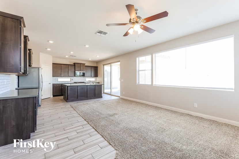 A spacious kitchen with a fan and a rug on the floor.