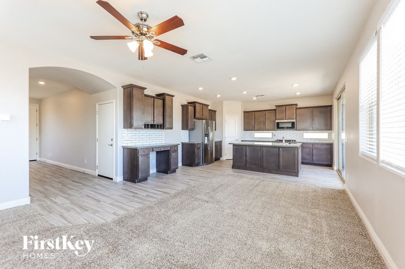 A spacious kitchen and living room with a ceiling fan and lighting.