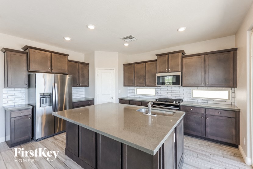 A modern kitchen with dark wood cabinets and stainless steel appliances.