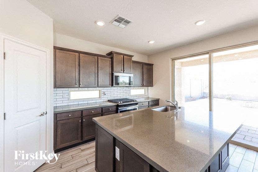 A kitchen with dark brown cabinets and a granite countertop.
