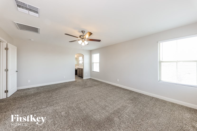 A spacious room with a ceiling fan and carpeted floor.