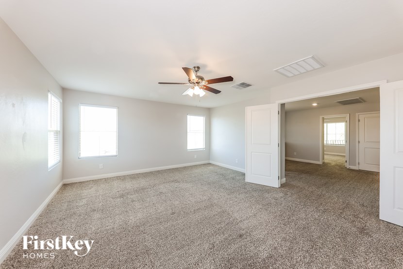 A spacious room with a ceiling fan and carpeted floor.