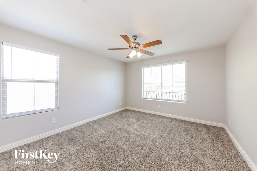 A spacious room with a ceiling fan and carpeted floor.