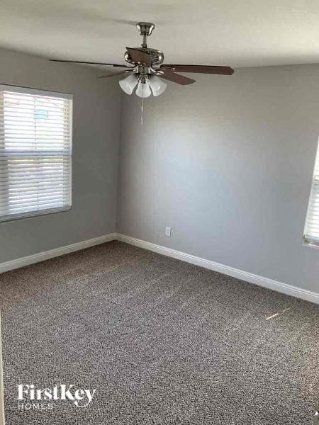 A room with a ceiling fan and a window with blinds.
