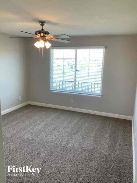 A room with a ceiling fan and a window with blinds.