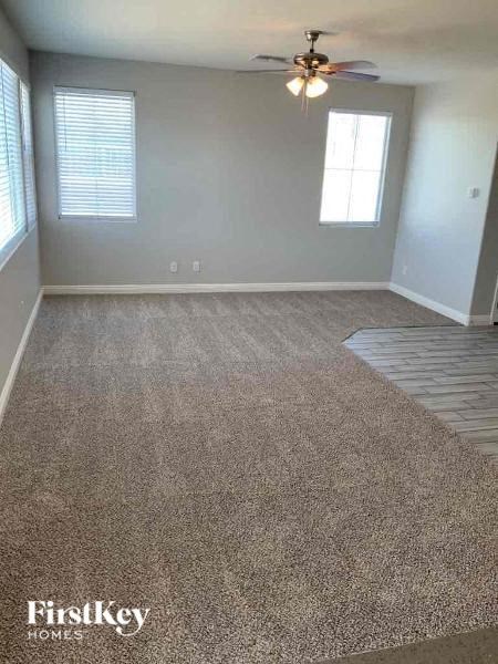 A room with a carpeted floor and a ceiling fan.