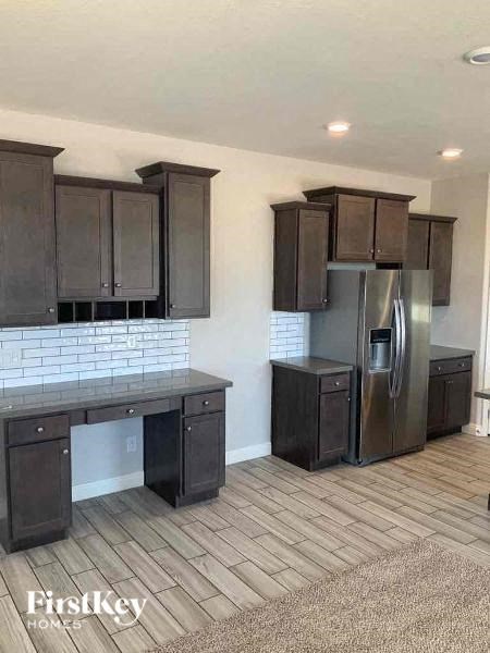 A kitchen with dark wood cabinets and a stainless steel refrigerator.