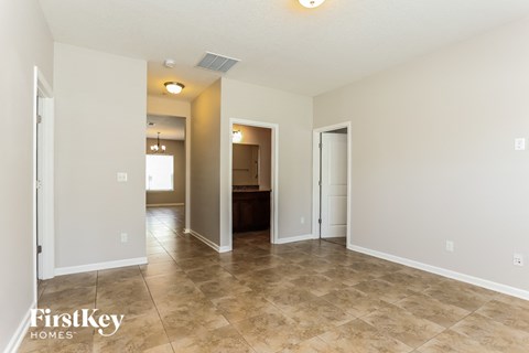 A spacious room with tile flooring and a doorway leading to another room.