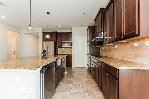 A kitchen with brown cabinets and a granite counter top.