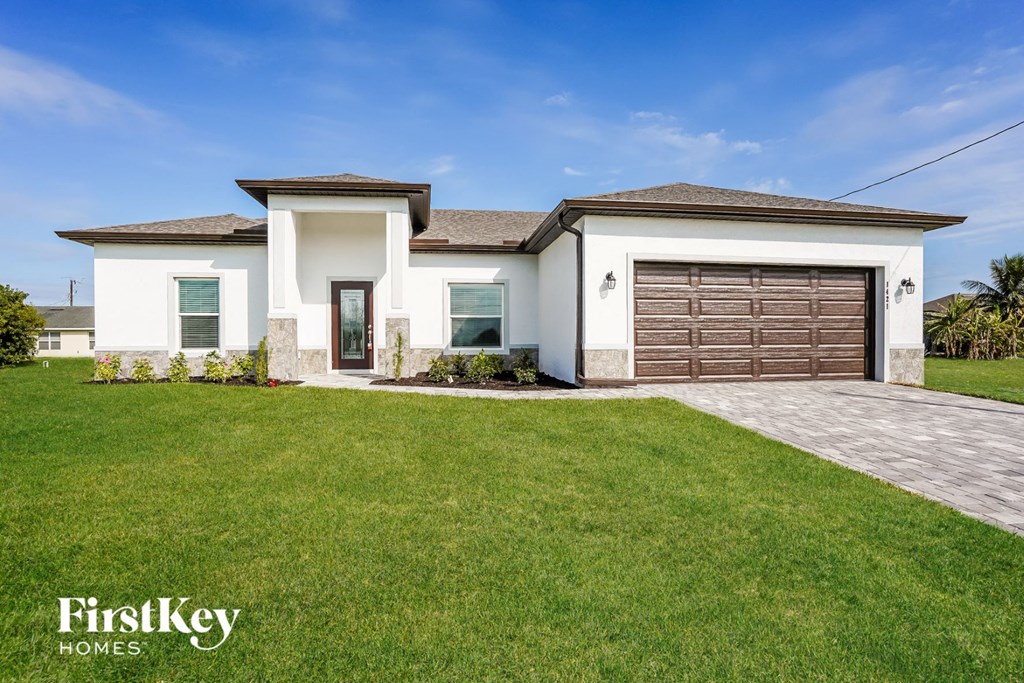 a white house with a garage and a green lawn