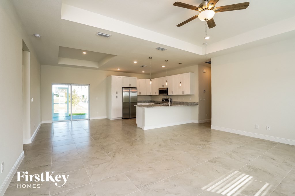 an empty kitchen and living room with a ceiling fan