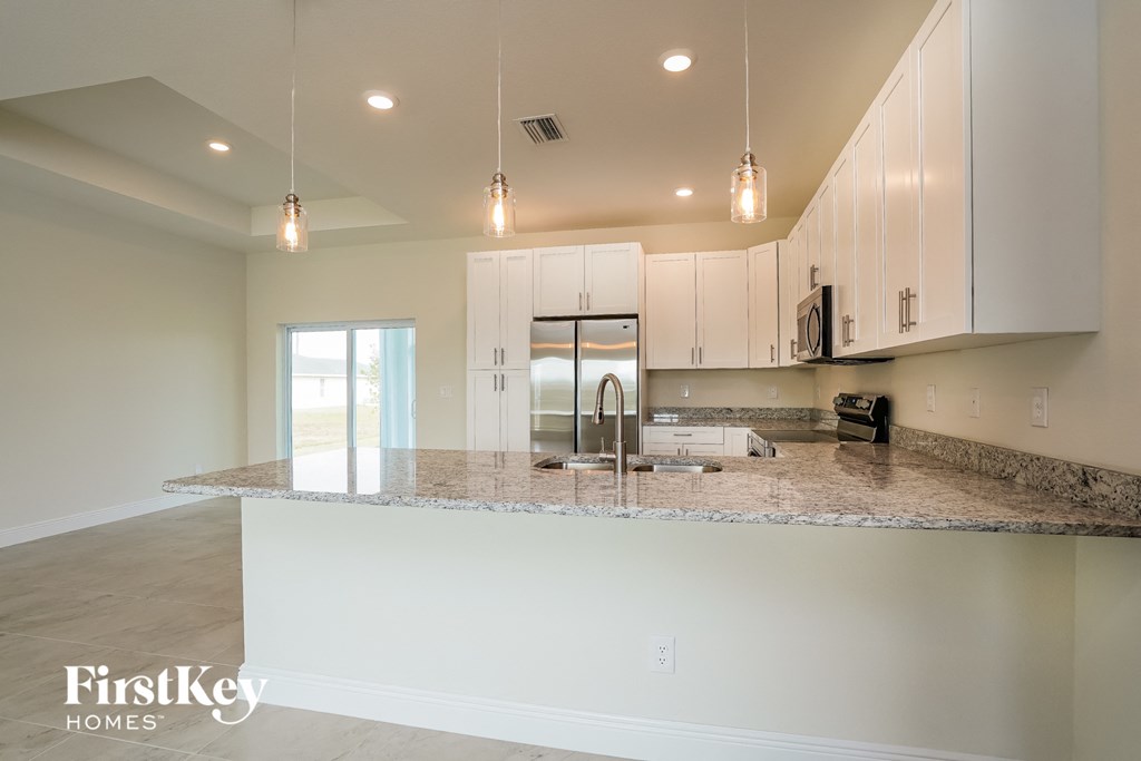 a kitchen with white cabinets and a granite counter top