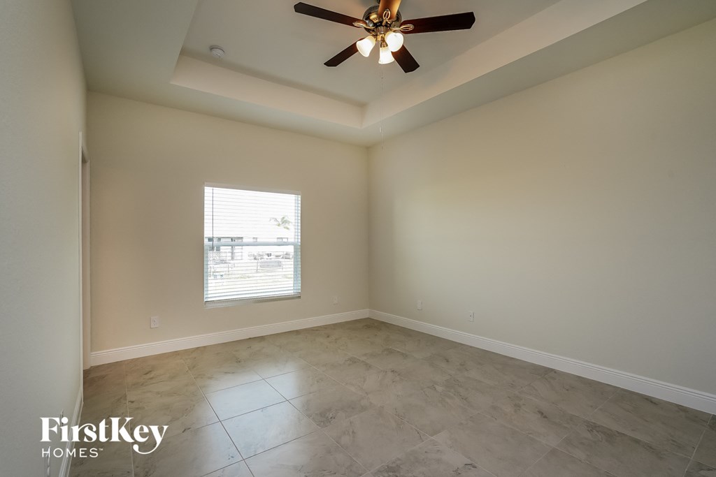 an empty living room with a ceiling fan and a window